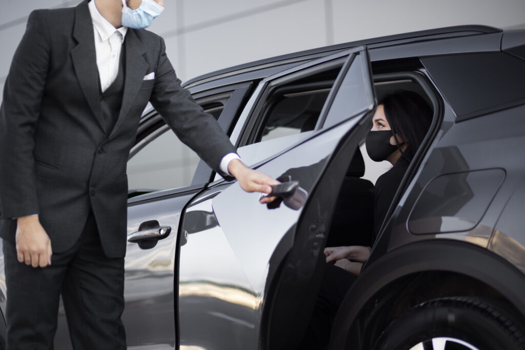 A man in a suit and a masked woman enter a car, representing a chauffeur service in Dubai.